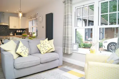 a living room with a couch and a kitchen at Secret Mersea Retreat - a stroll from the anchorage! in West Mersea