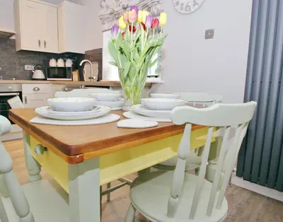a kitchen with a table with plates and flowers on it at Secret Mersea Retreat - a stroll from the anchorage! in West Mersea