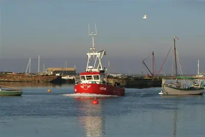 a red boat in the water next to other boats at Secret Mersea Retreat - a stroll from the anchorage! in West Mersea