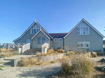 a large house with a staircase in front of it at Spinneys Beachfront home, Indoor Pool UK-Vacations in Thorpeness
