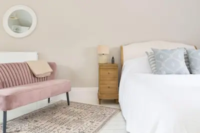 a bedroom with a bed and a chair and a mirror at Stylish and homely 1 bed Edwardian Coach House in Colchester