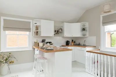 a kitchen with white cabinets and a counter top at Stylish and homely 1 bed Edwardian Coach House in Colchester