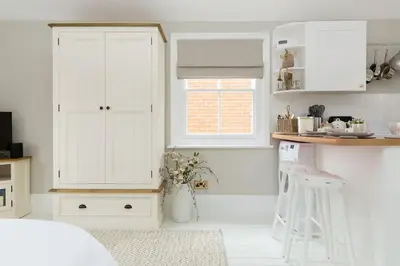 a kitchen with white cabinets and a vase of flowers at Stylish and homely 1 bed Edwardian Coach House in Colchester
