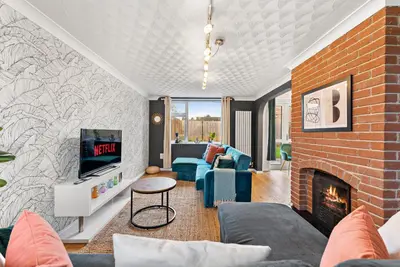 a living room with a fireplace and a brick wall at Boutique Cambridgeshire Gem in Fulbourn