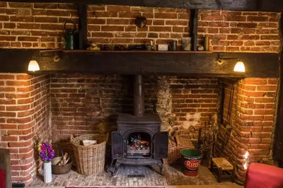 a brick fireplace with a stove in a brick wall at Toad Hall in Swilland