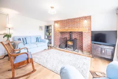 a living room with a couch and a fireplace at 3 Old School Cottages, Wissett in Halesworth