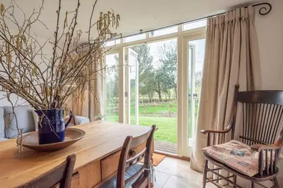 a dining room with a wooden table with a vase on it at 3 Old School Cottages, Wissett in Halesworth