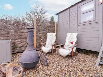 a backyard with two chairs and an outdoor stove at Bumble's Retreat in Whepstead