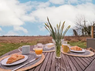 a picnic table with bread and orange juice and coffee at Bumble's Retreat in Whepstead