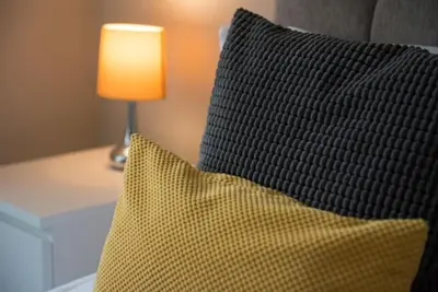 a pillow sitting on a bed next to a lamp at Cosy, Bright, 1 Bed Flat in Brentwood