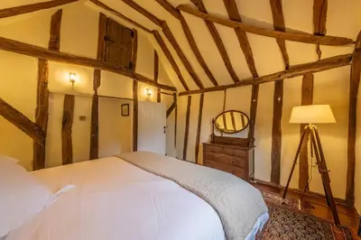 a bedroom with a bed and a lamp and a mirror at Medieval cottage in rural village - Duke's Lodge in Bildeston