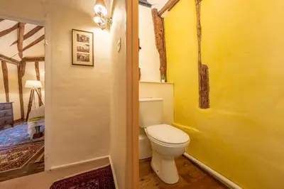 a bathroom with a toilet and a yellow wall at Medieval cottage in rural village - Duke's Lodge in Bildeston