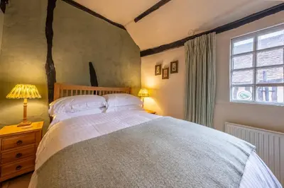 a bedroom with a large bed and a window at Medieval cottage in rural village - Duke's Lodge in Bildeston