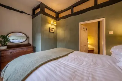 a bedroom with a large bed and a mirror at Medieval cottage in rural village - Duke's Lodge in Bildeston