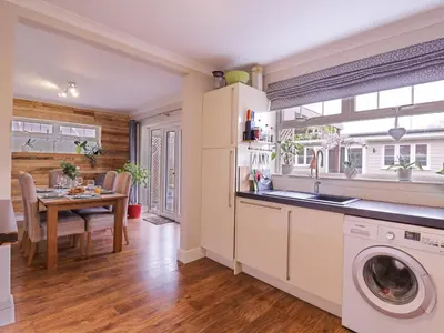 a kitchen with a washing machine and a dining room at Hide and Sleep in Walton-on-the-Naze