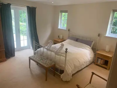 a bedroom with a bed and a bench and windows at Relaxing country cottage bungalow in Yaxley