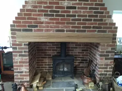 a brick fireplace with a stove in it at Relaxing country cottage bungalow in Yaxley