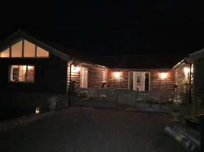 a house with lights on the front of it at night at Relaxing country cottage bungalow in Yaxley