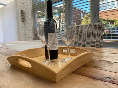 a bottle of wine and two glasses on a wooden tray at Shoreline hideaway - next to the beach in Holland-on-Sea