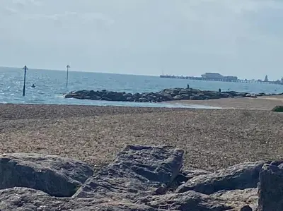 a beach with rocks on the sand and the ocean at Shoreline hideaway - next to the beach in Holland-on-Sea