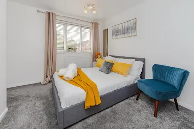 a bedroom with a bed and a blue chair at Lovely 2 Bedroom House in Cheshunt