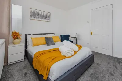 a bedroom with a large bed with a yellow blanket at Lovely 2 Bedroom House in Cheshunt
