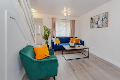 a living room with a blue couch and a table at Lovely 2 Bedroom House in Cheshunt