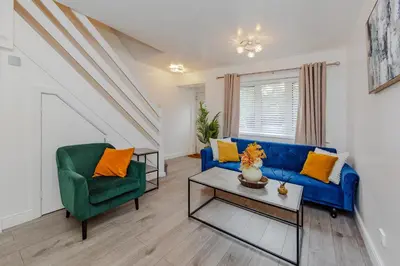 a living room with a blue couch and a green chair at Lovely 2 Bedroom House in Cheshunt