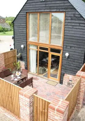 a backyard patio with a table and chairs at The Hayloft at Carpenters Farm in Colchester