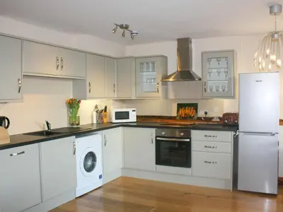 a kitchen with white cabinets and a white refrigerator at The Hayloft at Carpenters Farm in Colchester