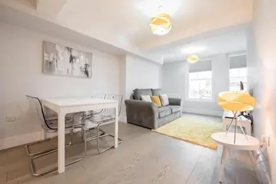 a living room with a table and a couch at Modern,central 1 bedroom flat in Brentwood