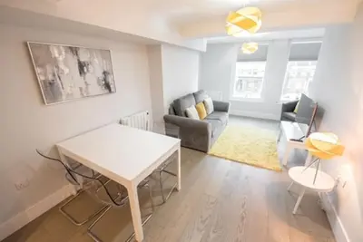 a living room with a table and a couch at Modern,central 1 bedroom flat in Brentwood