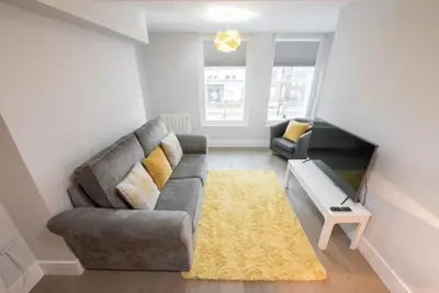 a living room with a gray couch and a yellow rug at Modern,central 1 bedroom flat in Brentwood
