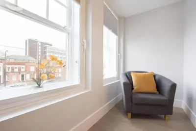 a chair sitting in a room with a window at Modern,central 1 bedroom flat in Brentwood