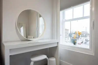 a white bathroom with a mirror and a window at Modern,central 1 bedroom flat in Brentwood