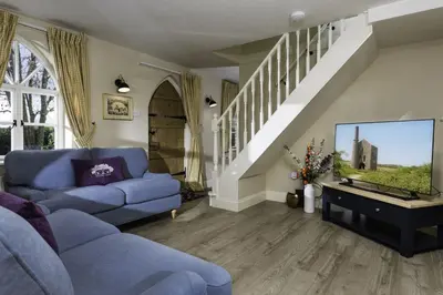 a living room with a blue couch and a tv at Crows Hall in Colchester