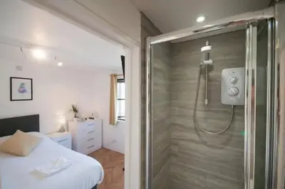 a bathroom with a shower and a bed in a room at Bellropes Countryside Retreat in Bradwell on Sea