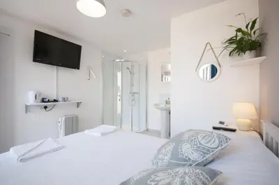a white bedroom with a bed and a television on the wall at Bellropes Countryside Retreat in Bradwell on Sea