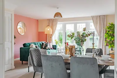 a dining room with a table and a green couch at Stylish & Spacious 3bed Home with Fast Wifi & Private Parking in Cambourne