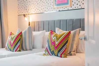 a hotel room with two beds with colorful pillows at Stylish & Spacious 3bed Home with Fast Wifi & Private Parking in Cambourne