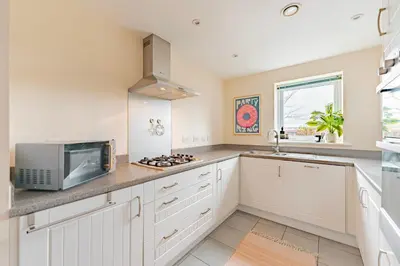 a kitchen with white cabinets and a microwave at Stylish & Spacious 3bed Home with Fast Wifi & Private Parking in Cambourne