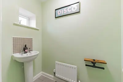 a bathroom with a sink and a sign on the wall at Stylish & Spacious 3bed Home with Fast Wifi & Private Parking in Cambourne