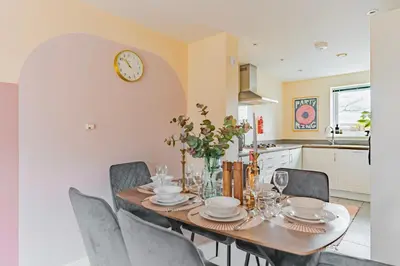 a dining room table with chairs and a clock on the wall at Stylish & Spacious 3bed Home with Fast Wifi & Private Parking in Cambourne