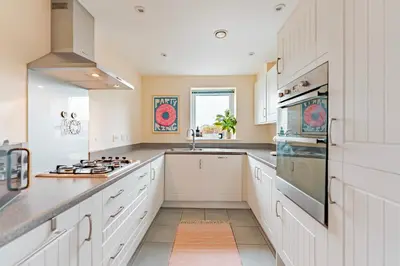 a kitchen with white cabinets and a sink at Stylish & Spacious 3bed Home with Fast Wifi & Private Parking in Cambourne