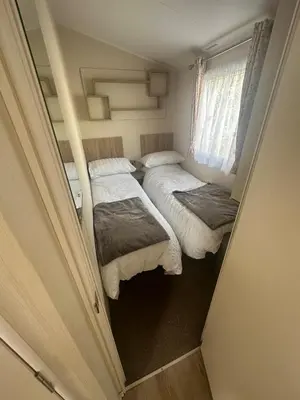 two beds in a small room with a window at 4 Bed 10 Berth Caravan Seawick Holiday Park in Saint Osyth