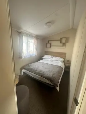 a small bedroom with a bed and a window at 4 Bed 10 Berth Caravan Seawick Holiday Park in Saint Osyth