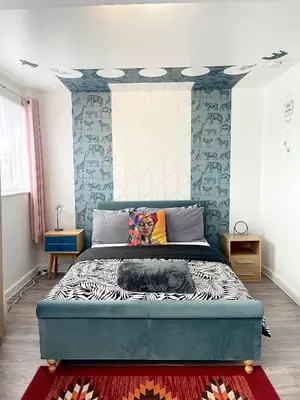 a bedroom with a large bed with blue walls at 12 Penn Gardens- Apart 2 in Friern Barnet