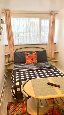 a bed in a room with a table and a window at 12 Penn Gardens- Apart 2 in Friern Barnet