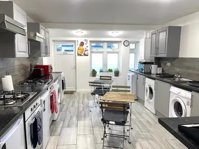 a kitchen with white appliances and tables and chairs at 12 Penn Gardens- Apart 2 in Friern Barnet