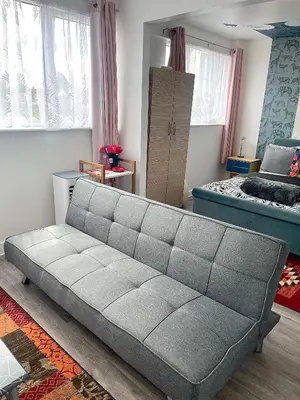 a gray couch in a room with a bedroom at 12 Penn Gardens- Apart 2 in Friern Barnet